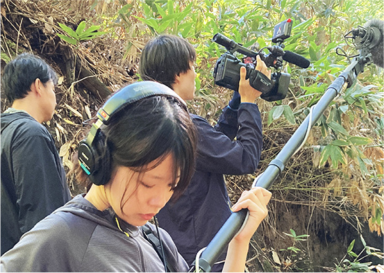 屋外撮影で音声機材やカメラを持つ技術部員